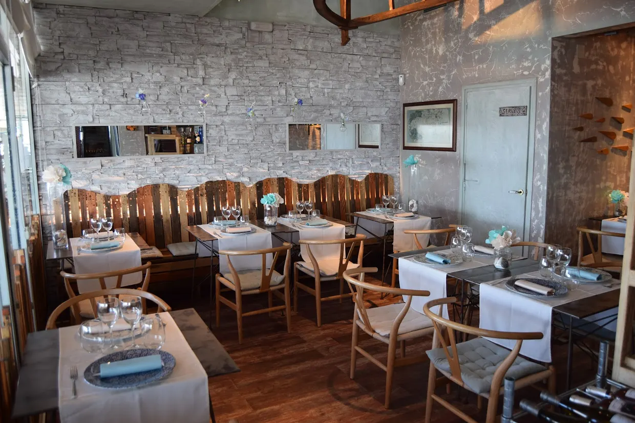 Sala interior amb paret de pedra vista i taules parades
